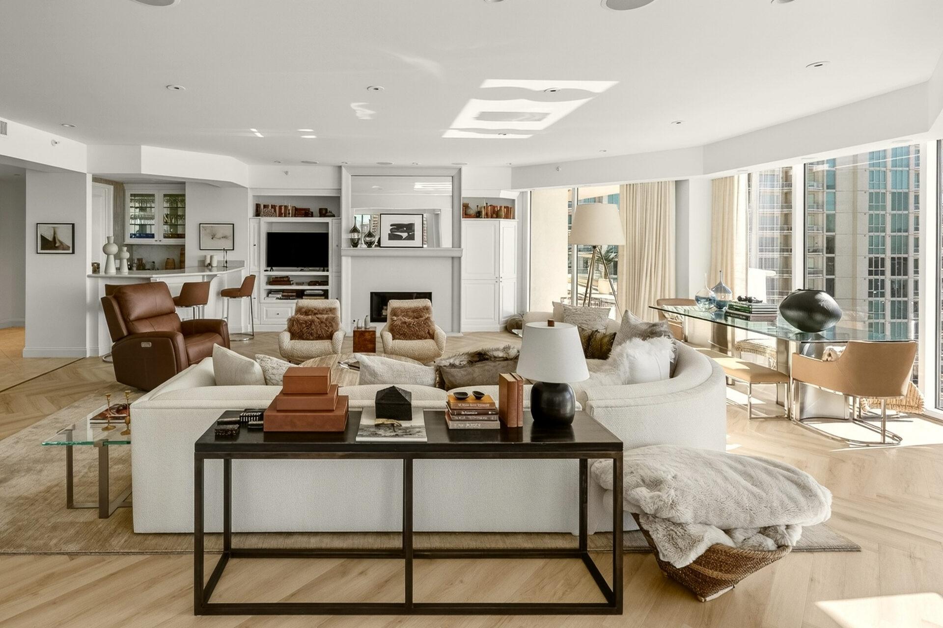 Bright, modern living room with white sofa, glass table, and warm wood floors.
